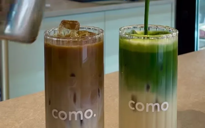 Een ijskoffie en een iced matcha in gemerkte COMO-glazen op de bar