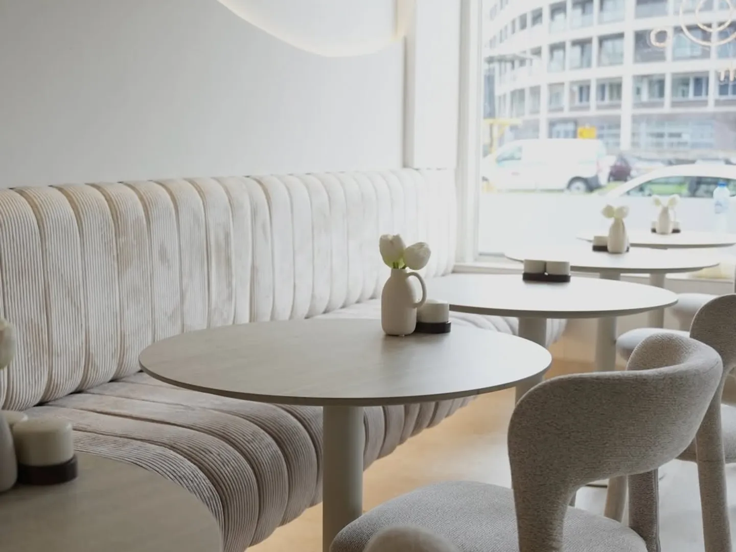 Ronde tafel bij het grote raam van COMO met de geribde bank erachter